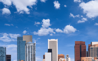 Downtown Phoenix skyline with modern office towers, palm trees, and a bright blue sky with white clouds.